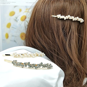 Barrettes dorées élégantes avec perles blanches et cristaux gris sur modèle et tissu