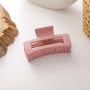 Close-up of a matte pink rectangular hair claw clip with a hollow design on white surface