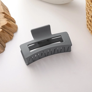 Detailed view of matte dark grey rectangular hair claw clip on minimalist background