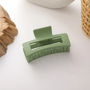 Close-up of matte bean green square hair claw clip with natural wood and straw decor