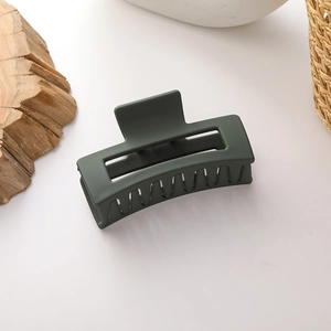Detail of dark green matte hair claw clip with rectangular cutout and spring mechanism