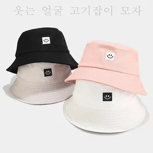 Dettaglio di quattro cappelli a secchiello in cotone con toppa sorridente in vari colori