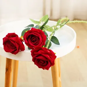 Detailed close-up of three artificial red roses with realistic silk petals and green leaves