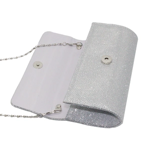 Macro view of silver glitter evening clutch bag with chain strap and magnetic snap closure