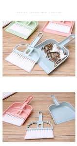 Mini handheld broom and dustpan set cleaning keyboard crumbs on wood surface