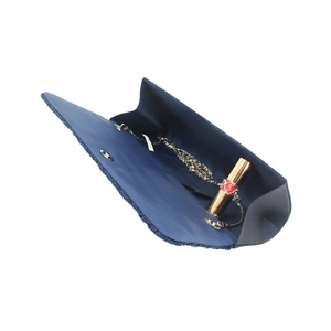 Détail d'une pochette en satin bleu marine avec chaîne argentée et rouge à lèvres