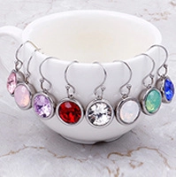 Detailed set of eight pairs of multi-color crystal drop earrings on a white cup rim