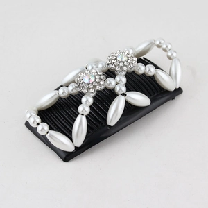 Detail of magic hair comb with white pearls and rhinestone flowers on black base