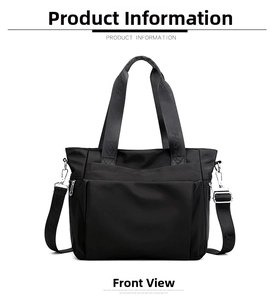 Detail of black nylon tote bag featuring wide logo handles and adjustable shoulder strap