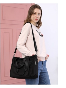 Detail of black nylon shoulder bag with adjustable wide strap shown on a model