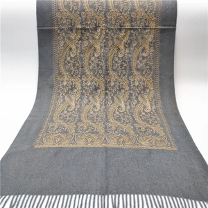 Detailed view of grey pashmina shawl featuring golden paisley embroidery and tassel trim