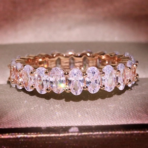 Luxurious rose gold eternity ring with oval-cut zircons on a textured fabric jewelry box cushion