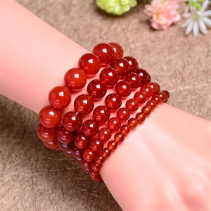 Close-up of stacked natural red agate bracelets showing beads from 4mm to 14mm size