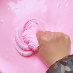 Close-up of hand squeezing pink cotton butter slime showing soft stretchy texture