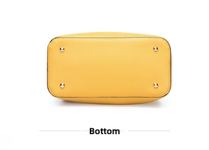 Detail view of the yellow tote bag bottom featuring four protective gold metal feet studs