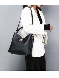 Side view of a black leather tote bag with brown snakeskin handle on a fashion model