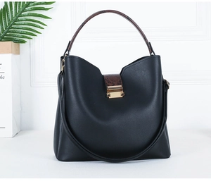 Detail view of black leather handbag with brown snake print accent and gold hardware