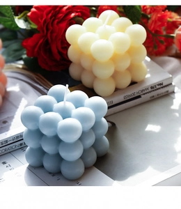 Dettaglio di candele profumate a bolle blu e crema con sfondo floreale elegante