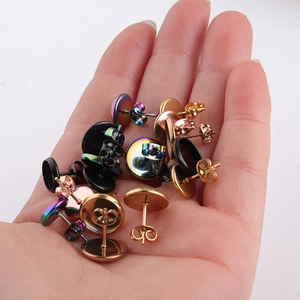 Close-up of stainless steel round stud earrings in gold, rose gold, and black in a palm