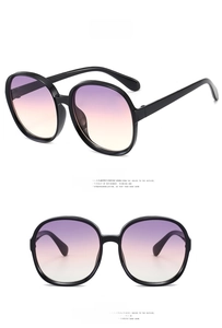 Detail of round oversized sunglasses with black frame and purple-pink gradient lenses