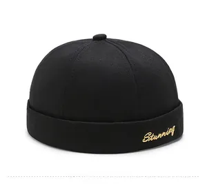 Detail of black cotton brimless docker hat with gold Stunning script embroidery