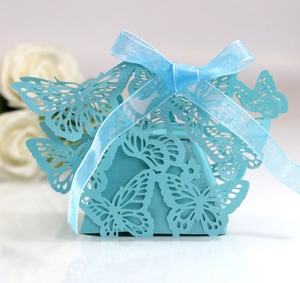Macro shot of laser-cut butterfly wedding favor box with blue ribbon and rose detail