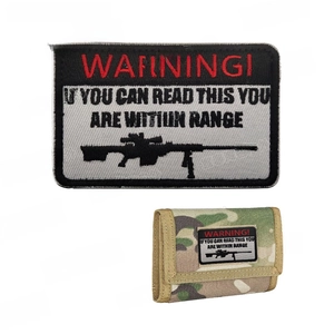 Tactical WARNING embroidery patch with rifle silhouette on a camo wallet hook and loop