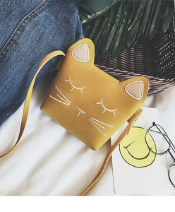 Detail of yellow cat-shaped crossbody bag for girls on white fabric background