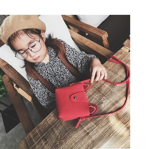 Close-up of a red kids cat ear crossbody bag with a metal snap on a little girl