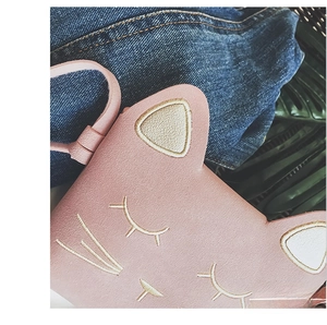 Close-up of pink cat-shaped bag with detailed facial embroidery and thin strap
