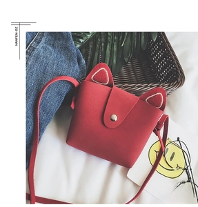 Detail of red cat-ear mini shoulder bag with magnetic flap closure and matte texture
