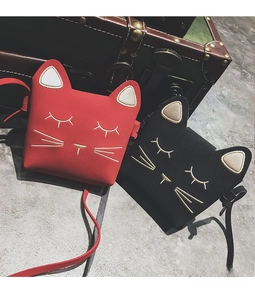 Close-up of cute cat-shaped crossbody bags in red and black with detailed gold embroidery