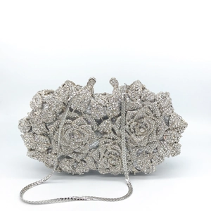 Detailed macro view of silver floral evening clutch with hollow roses and shiny rhinestones