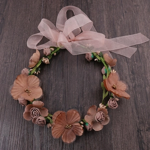 Detail of floral bridal headband with faux roses and ribbons on dark wood background
