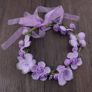 Detail of purple artificial rose wreath with satin bow for bridal or party wear