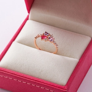 Close-up of rose gold ring with colorful gemstones in a pink velvet jewelry box