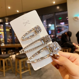 Detailed view of three silver rhinestone hair clips on a white display card