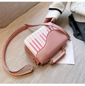 Close-up of pink piano key handbag featuring golden treble clef and leather top handle