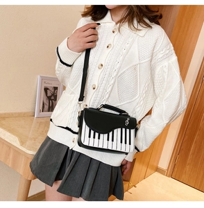 Detail view of piano keyboard bag featuring a silver treble clef metal charm decoration