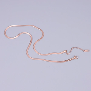 Detail of rose gold snake chain with lobster clasp and K18 hallmark on grey background