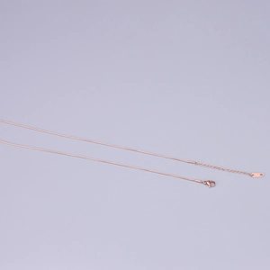 Close-up of rose gold snake chain necklace showing the K18 hallmark on the tag