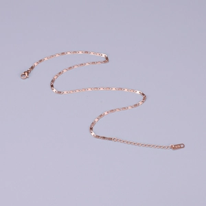 Macro detail of rose gold stainless steel chain with K18 hallmark stamp on tag
