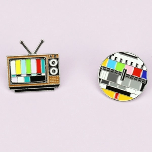 Macro view of vintage TV and circular test pattern enamel brooches with metal texture