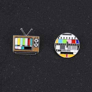 Detail view of colorful retro TV and signal test pattern enamel pin set on black texture