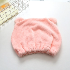 Pink microfiber bear-ear hair drying cap in soft coral fleece on a white wooden background