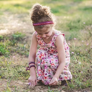 Detail of glitter baby headband with pink floral print romper in a natural outdoor setting