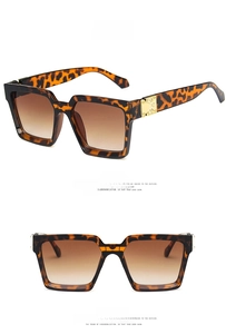 Détail de lunettes de soleil carrées léopard avec charnières dorées et verres dégradés