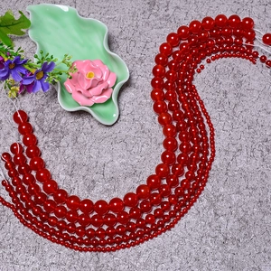 Detailed view of red agate round beads arranged in S-curve on textured background
