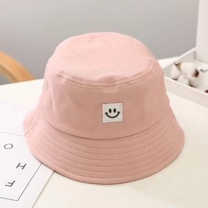 Close-up of pink cotton bucket hat with cute black smiley face patch for kids