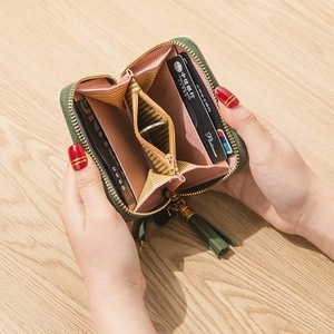 Green leather small zipper wallet with tassel and striped lining shown open in hands